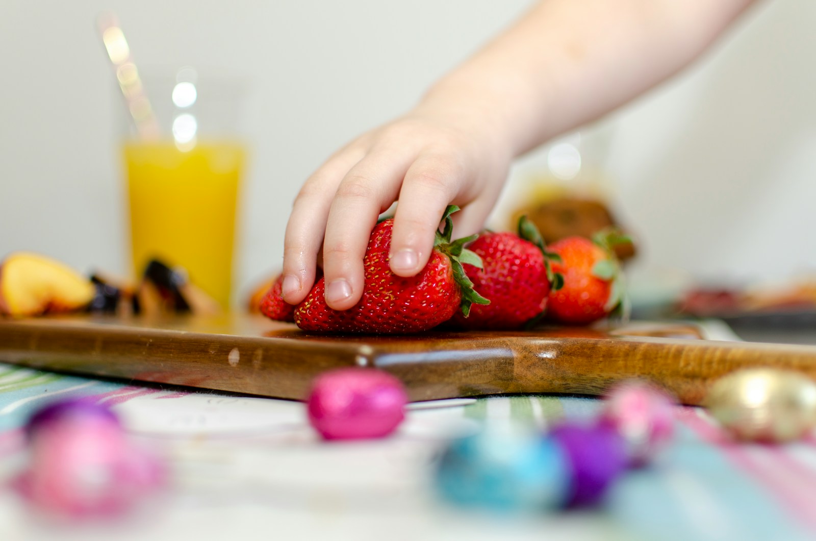 person holding strawberries on brown wooden chopping board