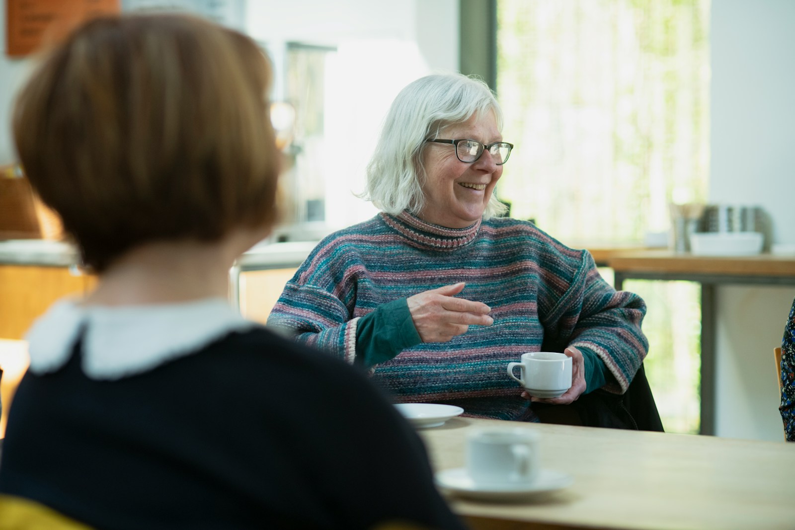 a woman sitting at a table talking to another woman